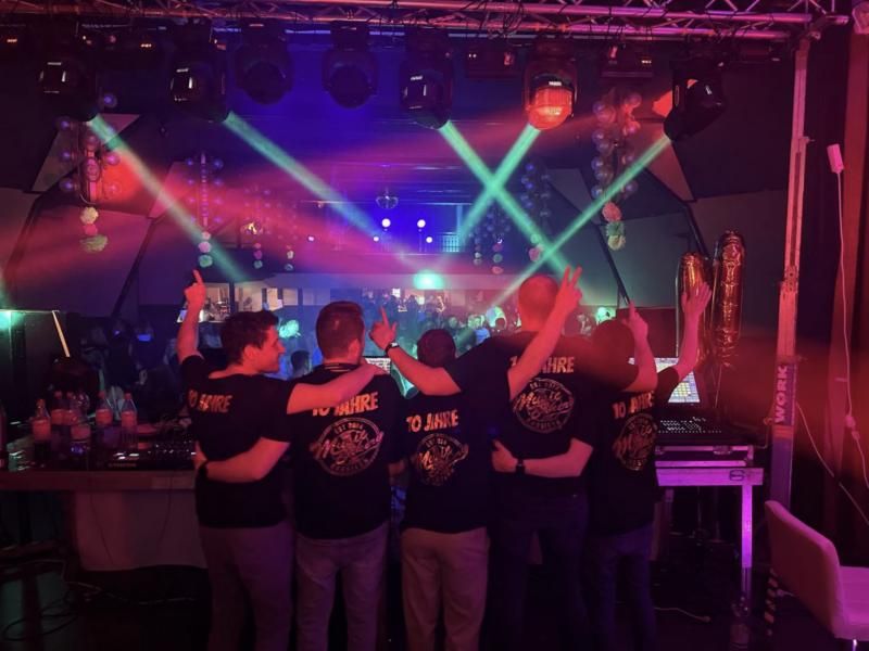 Crew vor einer Bühne mit Traversen, Moving Heads und Lichtstrahlen